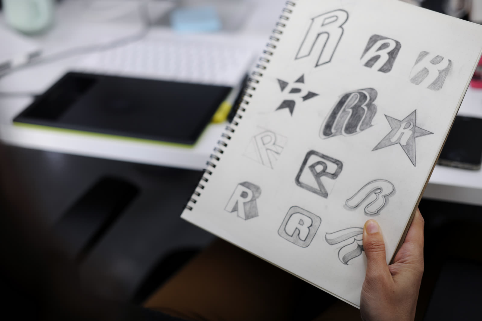 A small business owner reviewing logo design options on a laptop at their shop counter