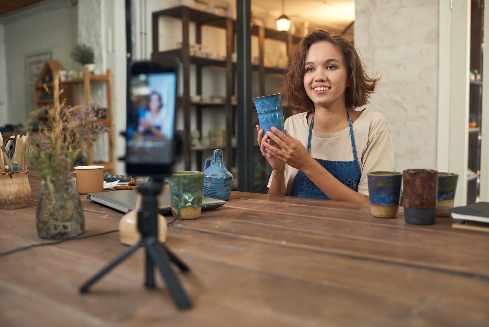 A small business owner filming a short video on a phone inside their shop