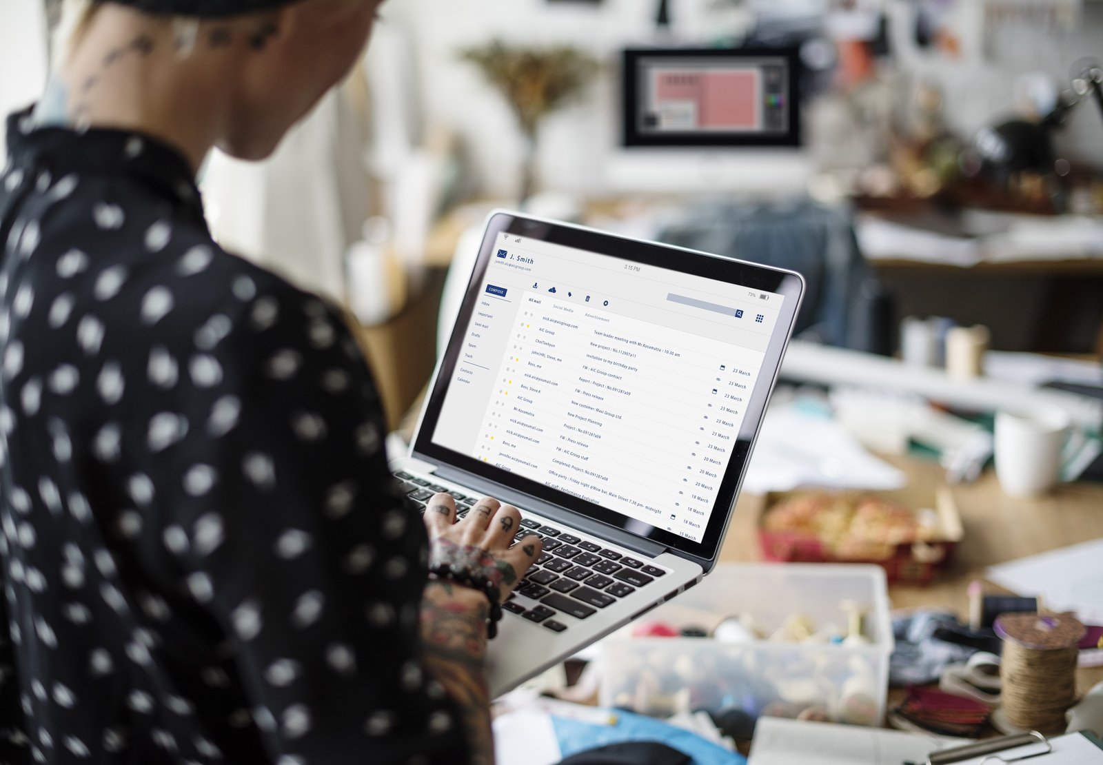 A small business owner checking email inbox and spam folder results on a laptop at a tidy front counter